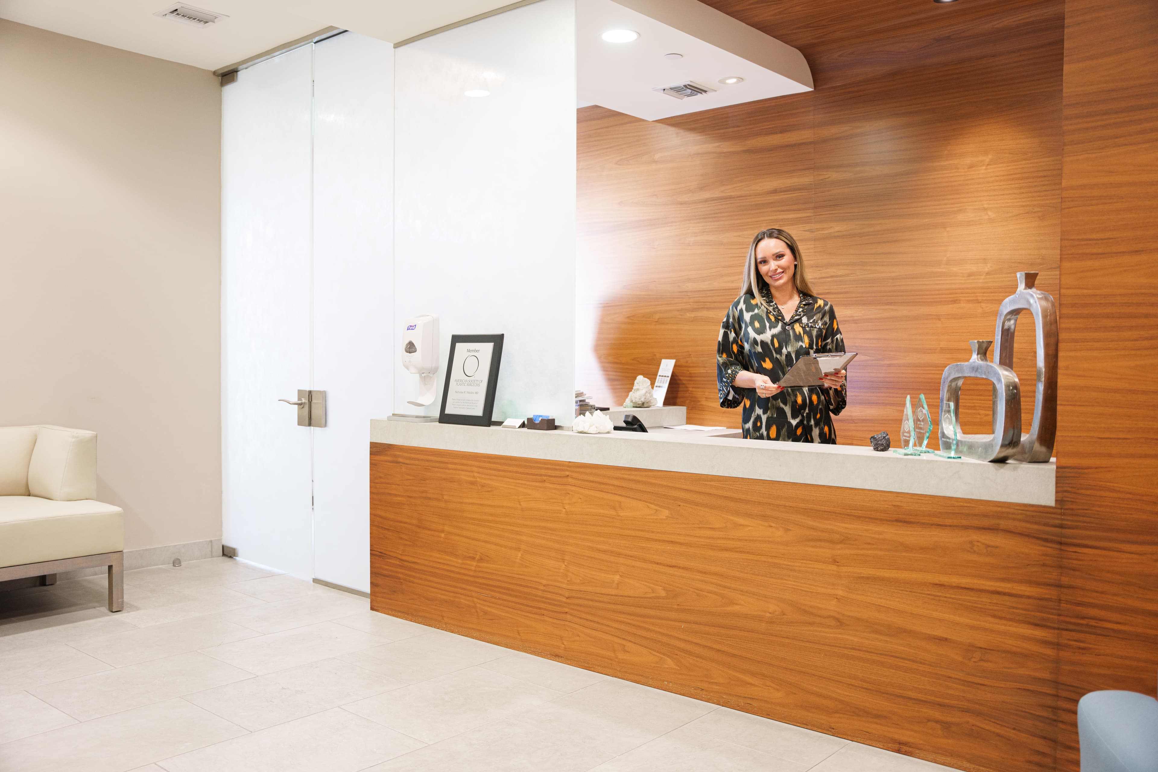 Receptionists greeting a patient at a warm, wood-panelled dental front desk